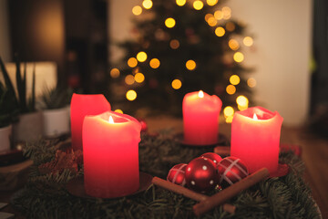 Adventskranz mit Kerzen und Weihnachtsbaum im Hintergrund