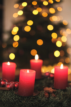 Adventskranz mit Kerzen und Weihnachtsbaum im Hintergrund