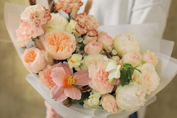 Young woman holding a bright bouquet of beautiful flowers in her hands. Colorful flower bouquet. Wrapped flowers bouquet.