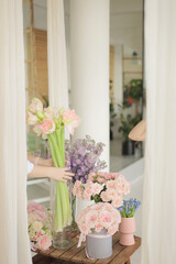 Different flowers in glass vase on wooden table. Pink roses, purple delphinium and peach amaryllis.