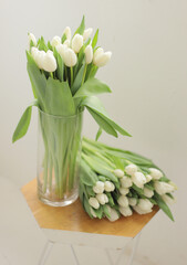 Bouquet of white tulips in glass vase on wooden table. Fresh flower for the gift. Bridal bouquet.