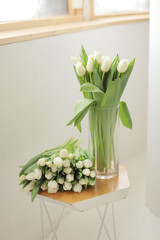 Bouquet of white tulips in glass vase on wooden table. Fresh flower for the gift. Bridal bouquet.