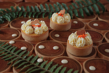 dessert, cheesecake with mango and passion fruit in the form of brownies with mousse on top. Decorated with cookies in the form of a heart. On a wooden table in a white plate