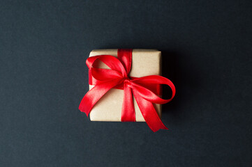 Festive concept - gifts with craft paper with a red bow on a black background. composition for christmas, new year and holidays. flat lay with place for text.
