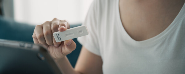 Asian young woman with hygiene protective face mask using SARS 2019-nCoV COVID-19 coronavirus antigen rapid test kit.