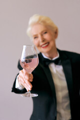 stylish mature sommelier senior woman in tuxedo with glass of wine. Fun, party, style, lifestyle, work, alcohol, celebration concept
