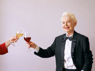 stylish senior sommelier woman in tuxedo with glass or red wine at the party. Beverage, mature, style, friendship concept