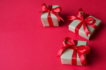 Festive concept - gifts with craft paper with a red bow on a red background. composition for christmas, new year and holidays. flat lay with place for text.
