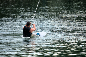 A man wakeboarding on a lake on summer day in a life  jacket. Soft focus. Action blur.