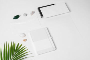 Stationery mockup for branding projects, with foliage elements such as palm leaf and granite, stones, shells, stick, A4 envelope, letter envelope, notebook, business card and letterhead.