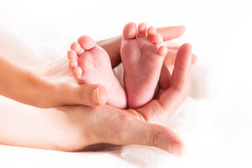 Obraz na płótnie Canvas Newborn baby feet in mom's hands