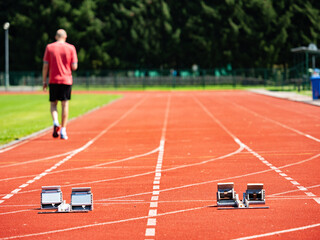 Obraz premium Sportsman walk on the running tracks after training. course. Starrting blocks at athletics stadium