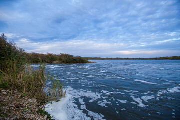 Photo of a blue lake against a background of sky and green grass. Nature concept