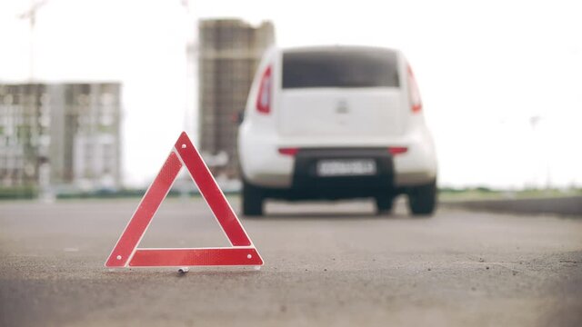 Warning triangle on road, broken car, malfunction, driver waiting for tow truck