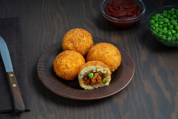 Arancini Italian or Sicilian cuisine rice balls stuffed with mince and green peas, coated with...
