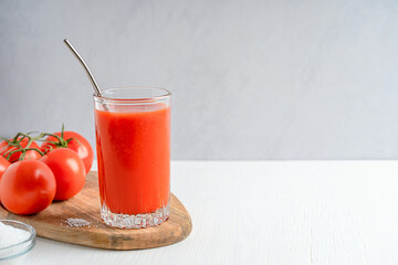 Refreshing salty tomato juice made of ripe red tomatoes served in tall drinking glass with metal...