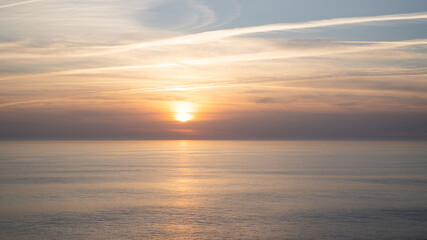 Portugal ocean sunset. Portuguese sky and sea. Pastel sunset with lines from airplanes. Airplane trails on sunset