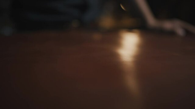 Tracking shot of male tailor hand smoothing leather piece on table at workshop, close up