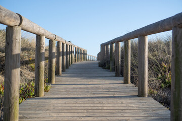 Wooden hiking bridge. Travel path in the wild. Log walkway heading to the sea. Portugal boardwalk