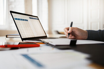 Working with documents and online spreadsheets. The man counts the company's revenue. Workplace in...