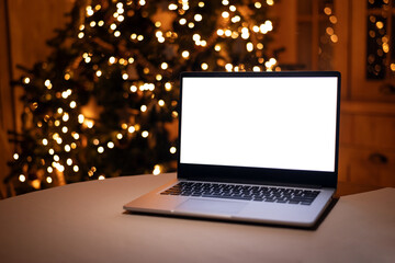 Front view of white screen laptop in home with christmas tree warm light. Remote work. freelance. Work from home. Telework.