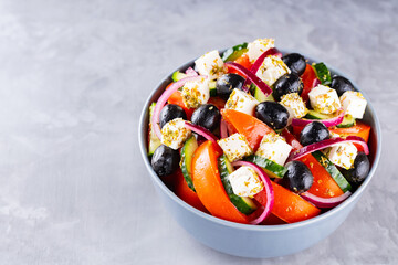 Greek salad with feta and olives on a gray background. Healthy mediterranean salad. Copy space. Top view