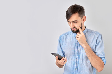 Serious pensive face man holding mobile phone and thinking isolated on white studio background