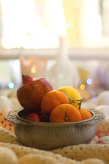 Silver bowl with various fruit, soft blanket and various Christmas decorations. Hygge at home. Selective focus.