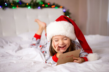 Merry Christmas and Happy Holidays. The little happy girl on the bed wrote a letter to Santa Claus...