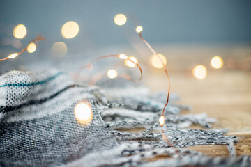 A warm plaid scarf with fringe lies.The garland is lit with lights.The concept of the Christmas and...