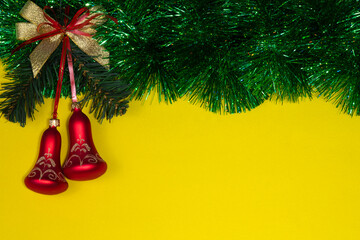 red christmas bells on a yellow background with green tinsel