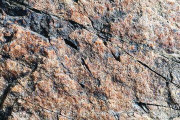 Texture of granite rock. Cracked stone surface from weathering. Close up of granite surface. Earth color concept