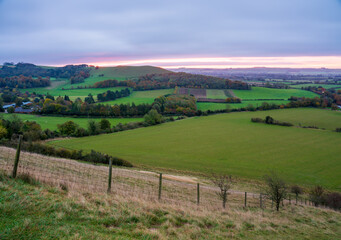 Fototapeta na wymiar beautiful morning sky as the sun rises over Giant's Grave and Oare village. View from South facing edge of the Marlborough Downs, Pewsey Vale, Wiltshire AONB 