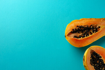 Summer composition. Tropical papaya fruits cut in half lie on a blue background. Summer concept. Flat lay, top view, copy space