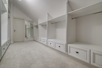 rows of shelves and clothes hangers in empty big wardrobe room in modern apartment or hotel