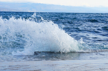 A rough sea surface and a wave lapping the shore