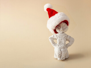 Prehistoric stone sculpture with Santas red hat on a bright background. Minimal creativ New Year and Christmas concept.