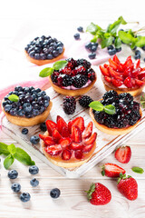 Fresh berries and ricotta cheese in tartletes. Summer dessert, healthy breakfast or snack, open sandwiches with strawberry, blueberries, blackberries. Top view.