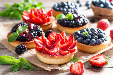 Fresh berries and ricotta cheese in tartletes. Summer dessert, healthy breakfast or snack, open sandwiches with strawberry, blueberries, blackberries.