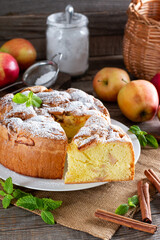 Homemade round sponge cake or chiffon cake with apples on white plate so soft and delicious with ingredients: eggs, flour, milk on table. Homemade bakery concept for background and wallpaper.