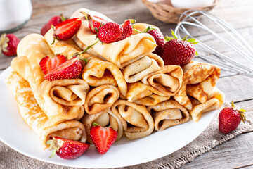 Many pancakes with strawberries. Maslenitsa. A stack of thin freshly baked pancakes with strawberry berries