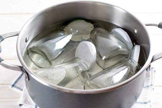 Sterilizing glass jars in a steel pan. Steaming bubbling wather