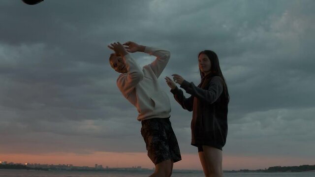 A guy and a girl are standing and fooling around on a motor boat at sunset. Romantic atmosphere.