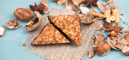 Fototapeta premium Nut corner, traditional german sweets called Nussecke, covered with chocolate, christmas baking, blue textured background