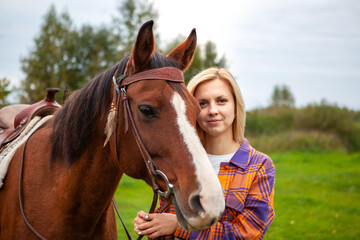 Beautiful young blond woman with a horse, portrait.