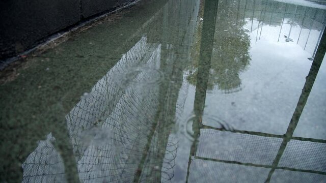 Prison chain link fence or rabitz with barbed wire reflects in the pond during the rain