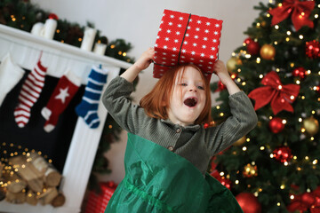 Red-haired girl holds a Christmas gift