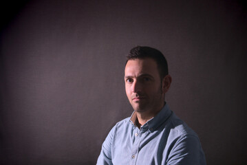Obraz premium Portrait of a stubble caucasian man in dark background with copy space