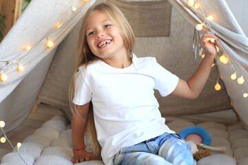 Girl in a white T-shirt plays in a wigwam © Zarya Maxim
