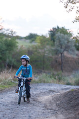 Little Boy riding his bicycle on a dirt road in the woods